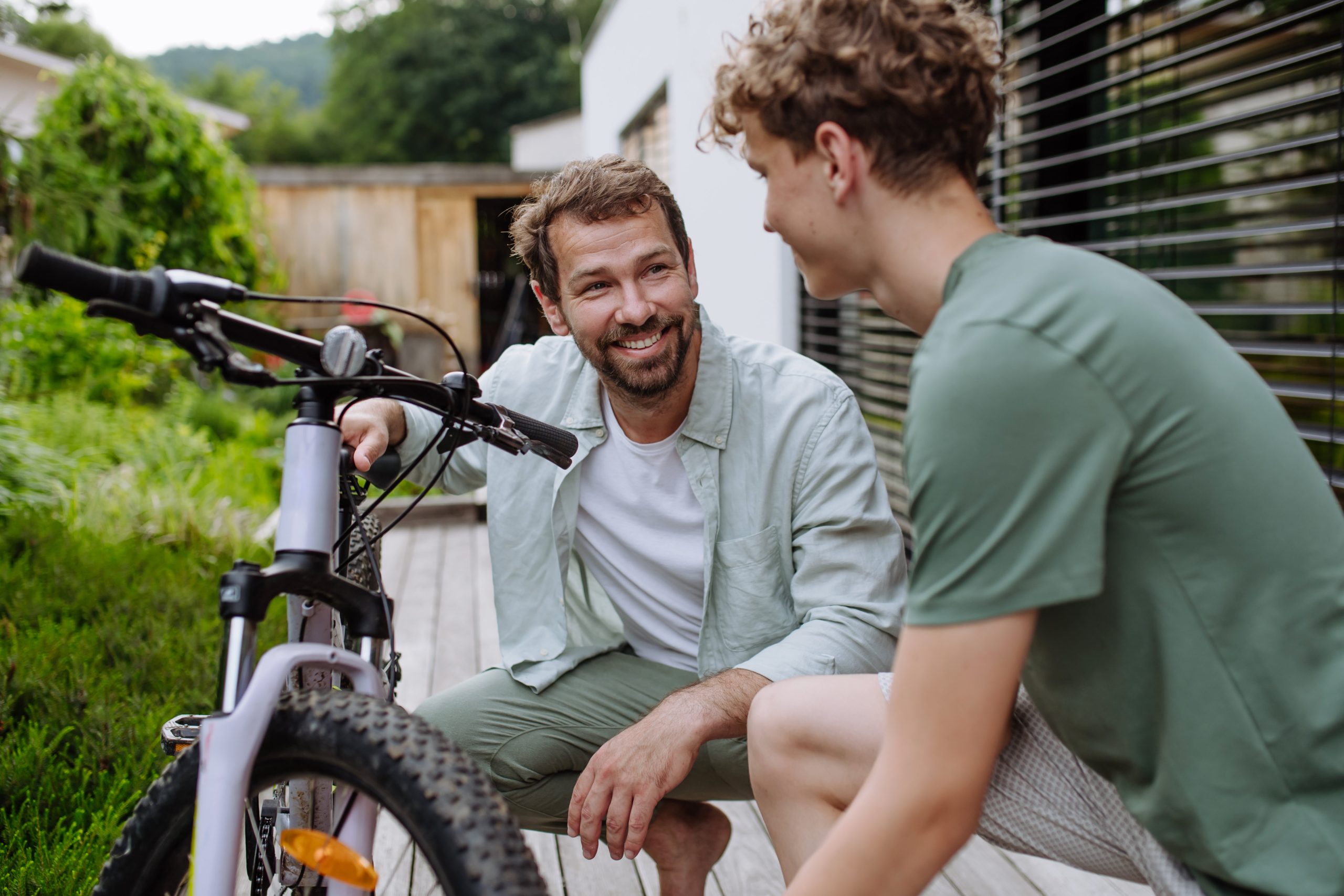 Dad and teenage son sitting with a bike